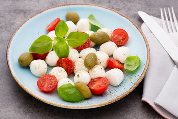 Delicious caprese salad with ripe cherry tomatoes and mini mozzarella cheese balls with fresh basil leaves.