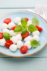 Delicious caprese salad with ripe cherry tomatoes and mini mozzarella cheese balls with fresh basil leaves.