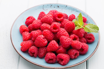 Fresh raspberries in a plate on a  vintage background.
