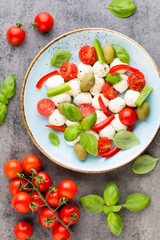 Delicious caprese salad with ripe cherry tomatoes and mini mozzarella cheese balls with fresh basil leaves.
