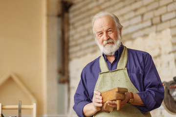 close up portrait of old male doesn't know how to work with wooden plane. look at the camera