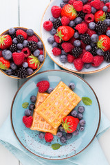 Fresh berry salad on blue dishes. Vintage wooden background.