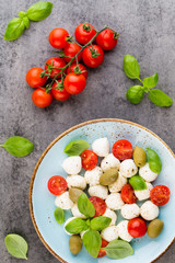 Delicious caprese salad with ripe cherry tomatoes and mini mozzarella cheese balls with fresh basil leaves.