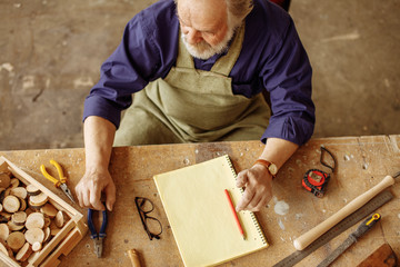 close up top view image of senior citizen sitting at the desk which is cluttered with instruments