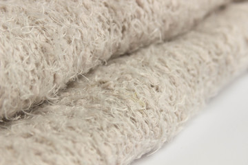 Fototapeta na wymiar Soft plaid with fringes, cozy beige fabric texture, close-up, white background
