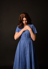 Obraz premium 3/4 portrait of brunette lady wearing blue dress. posed on black studio background.