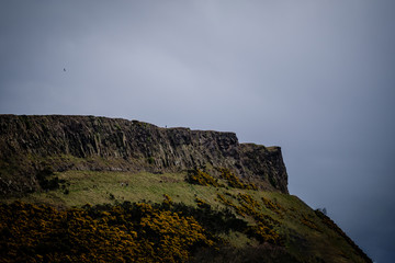 Man standing alone at Salisbury Crags in Edinburgh during a cloudy day, telephoto