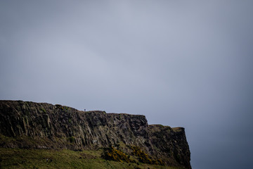 Man standing alone at Salisbury Crags in Edinburgh during a cloudy day, telephoto