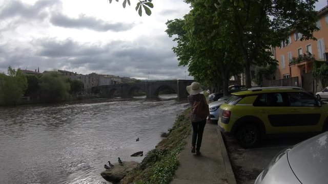Young woman with a hat strolling along the river Aude in the French town of Limoux, Languedoc in the south of France