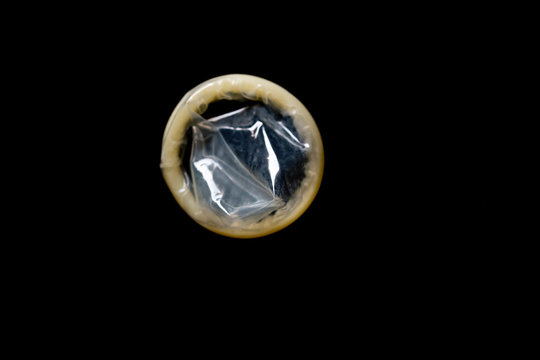 ein transparentes Kondom vor schwarzem Hintergrund, Freisteller