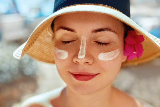 Facial Care. Female Applying Sun Cream and Smiling. Beauty Face.  Portrait Of Young Woman Smear  Moisturizing Lotion on Skin. SkinCare