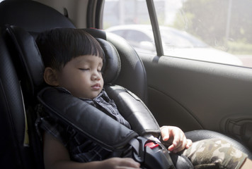 Toddler boy sleeping in car seat.