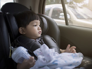 Toddler boy sitting in car seat.