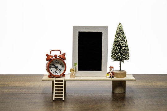 Blank black photo frame with Santa and Angel with Christmas tree and red alarm clock