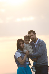 Portrait of a young couple with a child having fun in nature, sunset