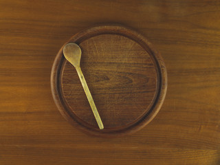 Round wooden cutting board with a wooden spoon resting on a wooden table