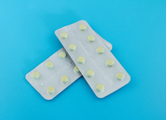 A pack of yellow pills on a blue background