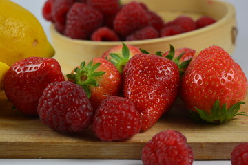 Strawberries, raspberries and a lemon on a white background