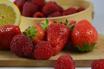 Strawberries, raspberries and a lemon on a white background