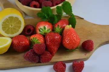 Strawberries, raspberries and a lemon on a white background