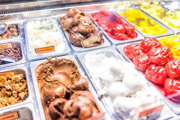 Ice cream frozen yogurt colorful serving counter parlour with many scoopable flavors, sorbet, chocolate, toppings signs