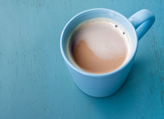 Milk coffee in a blue cup on pastel blue wooden floor
