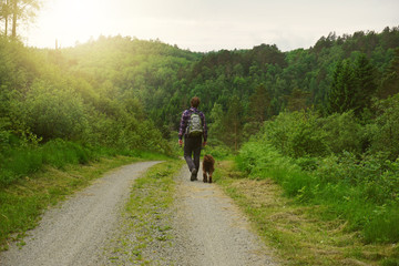 Mann geht mit Hund auf einem Weg während Sonnenuntergang