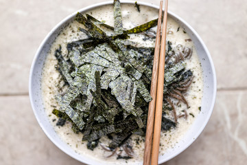 Macro closeup of soba buckwheat noodles Japanese soup with nori seaweed, ginger, green coconut broth on hot, cold summer, bamboo chopsticks flat top view © Kristina Blokhin