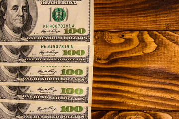 Many one hundred dollar bills on wooden table