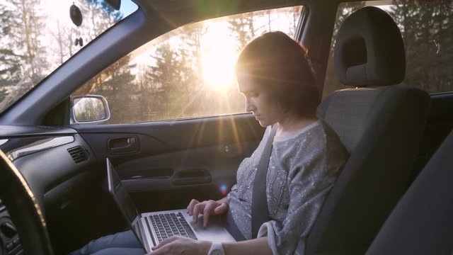 Woman businesswoman working with laptop in car salon. Girl with laptop sitting in car.