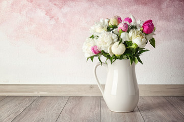Vase with bouquet of beautiful flowers on floor