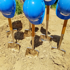 industrial blue hard hats on shovels in dirt for ground breaking ceremony