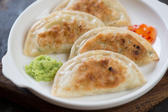 Closeup of pan fried korean potstickers served on a white plate, selective focus
