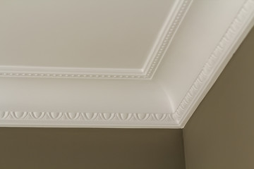 Ornamental white molding decor on ceiling of white room close-up detail. Interior renovation and...
