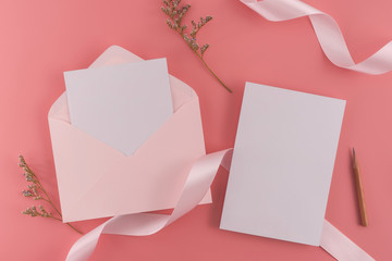 A wedding mock up concept. Wedding Invitation, envelopes, cards Papers on pink background with ribbon and decoration. Top view, flat lay, copy space