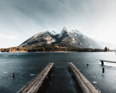 Gefrorener See im Sp&auml;twinter in den Alpen mit blick auf gewaltiges Bergmassiv und kleinem Holzsteg im vordergrund im Bild Hintersee und Watzmann