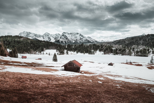 Gefrorener Bergsee in den Alpen mit Blick auf ein paar Holzh&uuml;tten den Geroldsee und die Berge im Hintergrund