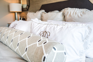 Closeup of new bed comforter with decorative pillows in bedroom in staging model home apartment or house