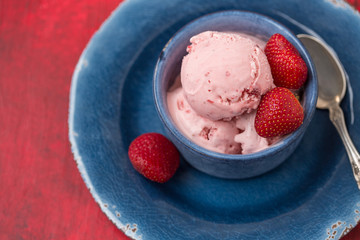 Homemade Strawberry Ice Cream in a Blue Bowl against a Red Background