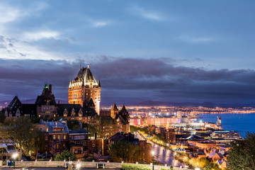 Cityscape or skyline of Quebec City, Canada, Chateau Frontenac, park and old town streets during purple sunset with illuminated castle, red Espace 400e building