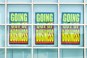 Closeup of yellow store closing banner poster sign on glass window of store building for bankruptcy going out of business