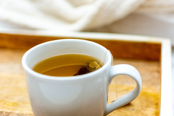 Hot tea in wooden tray on bed with white blankets relax room for text background copy mug