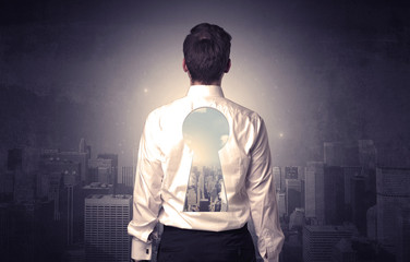 Young businessman standing and thinking with keyhole on his back and city graphic around