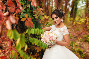 sexy bride standing near the colorful tree in autumn forest