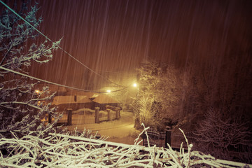 Snow is falling on deserted streets, winter night in village