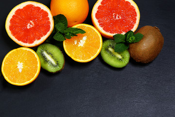 Variety of fruits grapefruit, oranges, kiwi, lemon, mint bunched together on a shale board, the concept of healthy eating, copy space, top view set