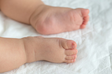 Little baby feet on white soft cloths in the background.
