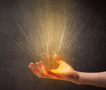 Yellow ray of light coming from a young hand 
