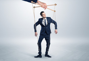 Puppet businessman in an empty room leaded by a huge hand
