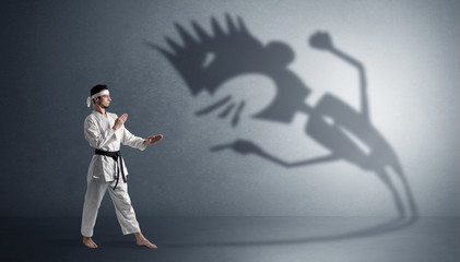Young karate man fighting with a big black scary shadow
